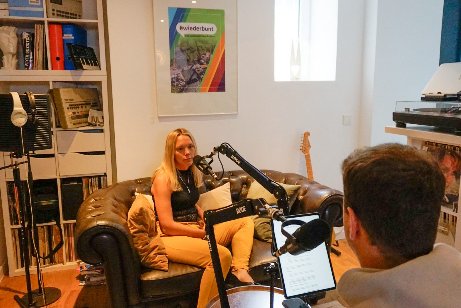 Nadine Wenigmann bei der Podcast-Aufnahme Nadine Wenigmann sitzt auf einem Sofa vor einem Mikrofon. Ihr gegenüber sitzt der Moderator Marius Reichert. Sie sitzen beide in einem Tonstudio.